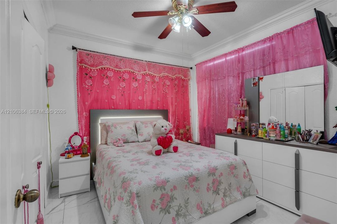Room featuring crown molding, neutral-toned flooring, and a ceiling fan with integrated lighting