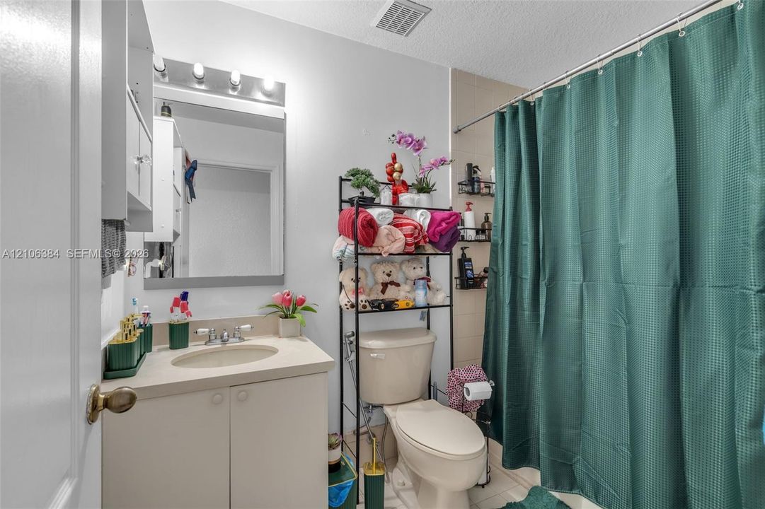 Bathroom featuring a vanity with a solid-surface countertop, an integrated sink, a multi-bulb light fixture, a framed mirror, and a tub-shower combination with wall tiling