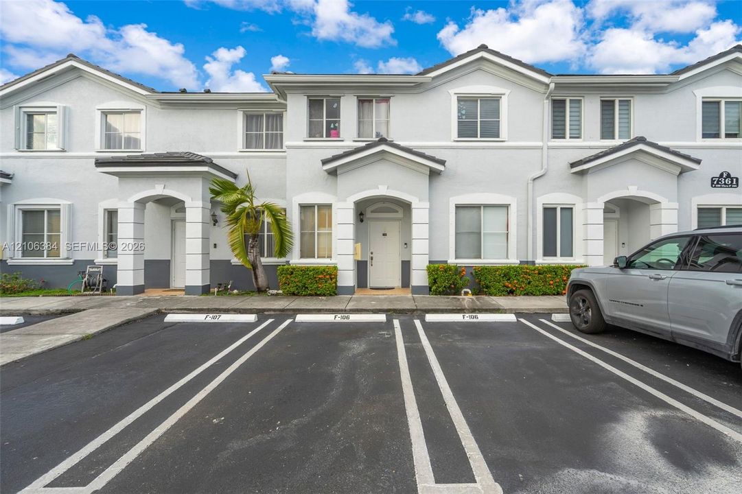 Two-story stucco exterior featuring covered entryways, multi-pane windows, and tile roofing