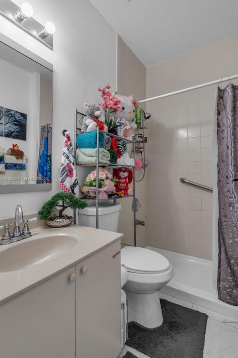 Bathroom featuring a vanity with an integrated sink, a wall-mounted vanity mirror, a dual-light fixture, and a bathtub with a tiled surround and grab bar