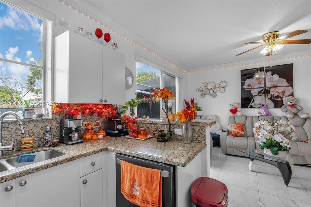 Kitchen featuring stone countertops, white cabinetry, a stainless steel undermount sink, and tile flooring