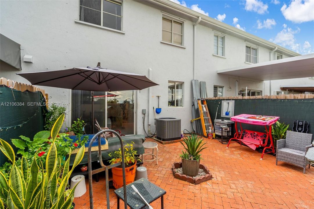 Patio area featuring herringbone-patterned brick pavers, sliding glass entry door, and an attached covered area