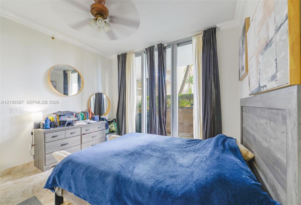Floor-to-ceiling windows with sliding glass doors, neutral tile flooring, crown molding, and a ceiling fan with integrated lighting