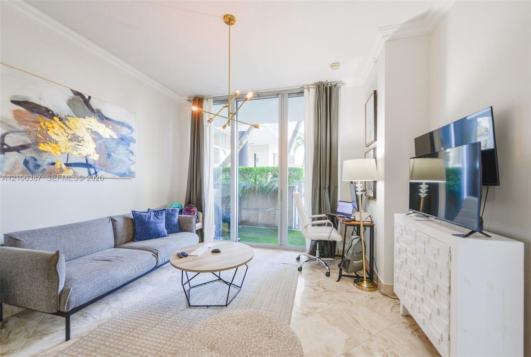 Floor-to-ceiling glass panel door, polished stone flooring, crown molding, and modern gold-finish multi-arm chandelier