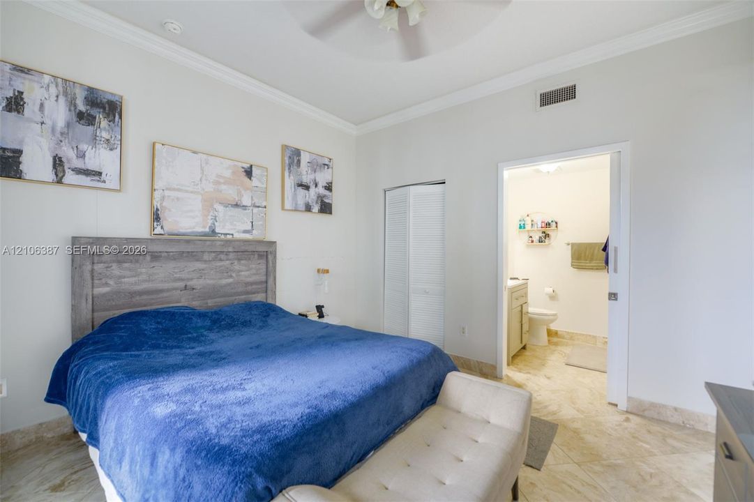 Room featuring stone-finish flooring, crown molding, a ceiling fan, and a sliding door