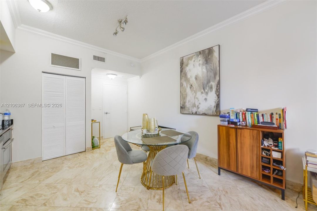 Neutral-toned tile flooring, white walls with crown molding, and louvered double-door closet