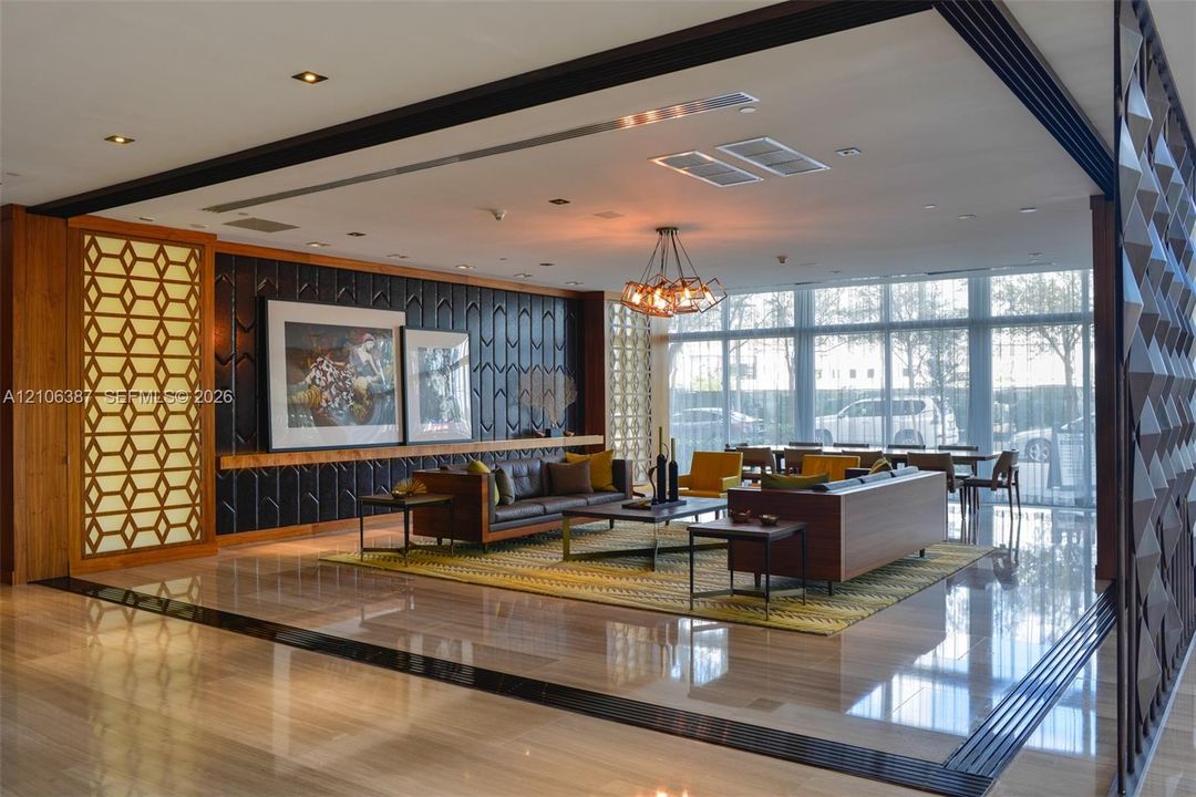 Polished stone flooring, floor-to-ceiling windows, textured accent wall with geometric wood-finish panels, built-in recessed lighting, and multi-tiered chandelier