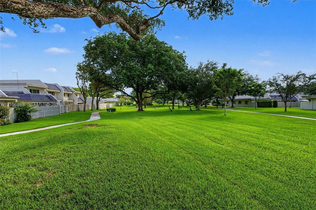 Expansive lawn featuring mature trees and paved walkways
