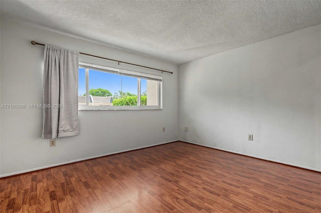 Interior room featuring wood-finish flooring, a multi-pane horizontal window, and a textured ceiling