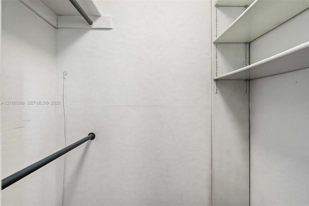 Storage area featuring adjustable shelving units, a horizontal hanging rod, and an overhead shelf