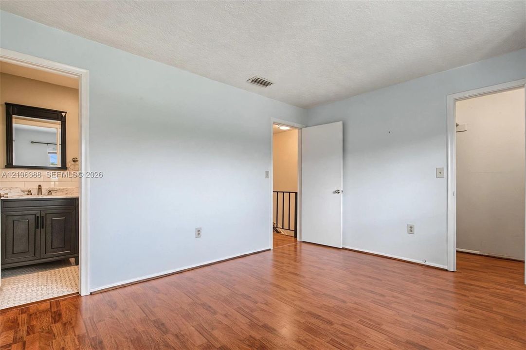 Interior space featuring wood-finish flooring, two interior doors, and a vanity area with built-in cabinetry and wall-mounted mirror
