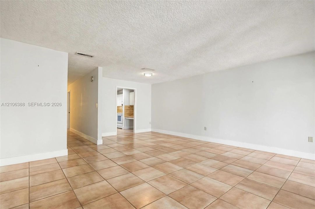 Open-concept living space featuring large-format ceramic tile flooring, neutral wall tones, and overhead flush-mount lighting