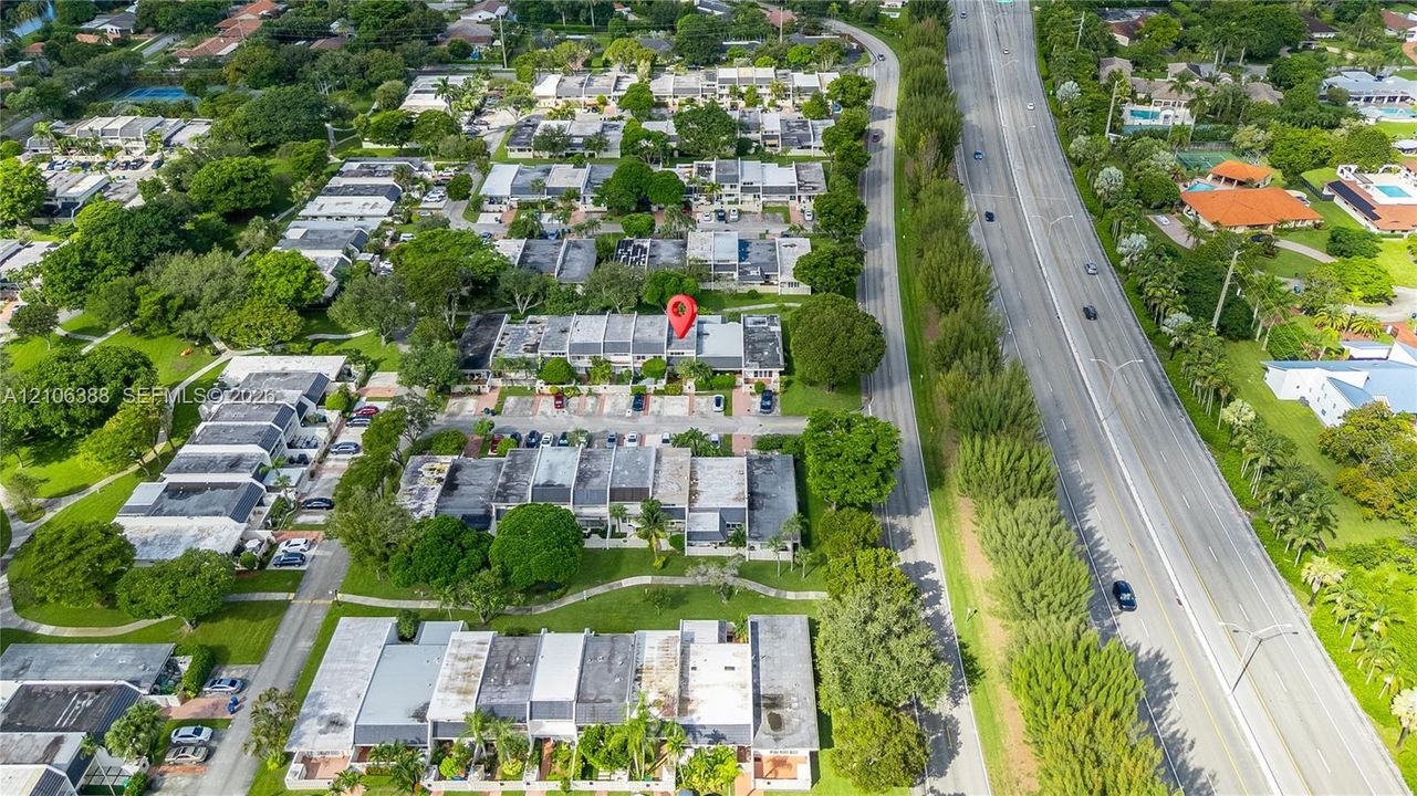 Aerial perspective featuring multi-unit residential structures, paved parking areas, and mature tree canopy throughout the grounds