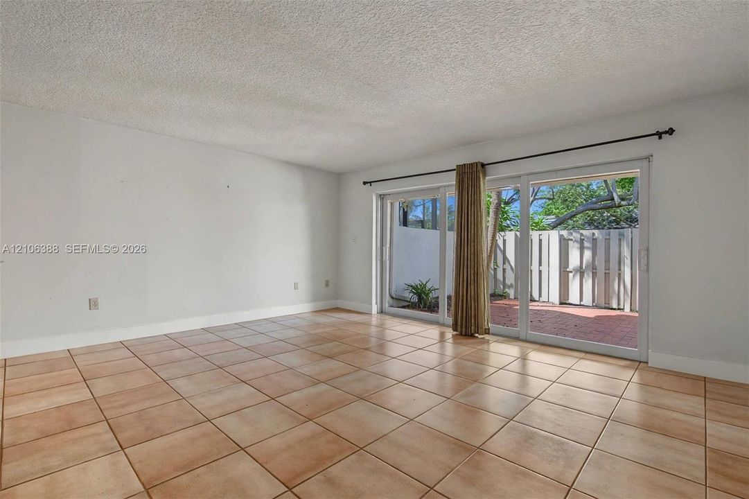 Spacious room featuring large-format square tile flooring, neutral wall tones, and glass sliding doors
