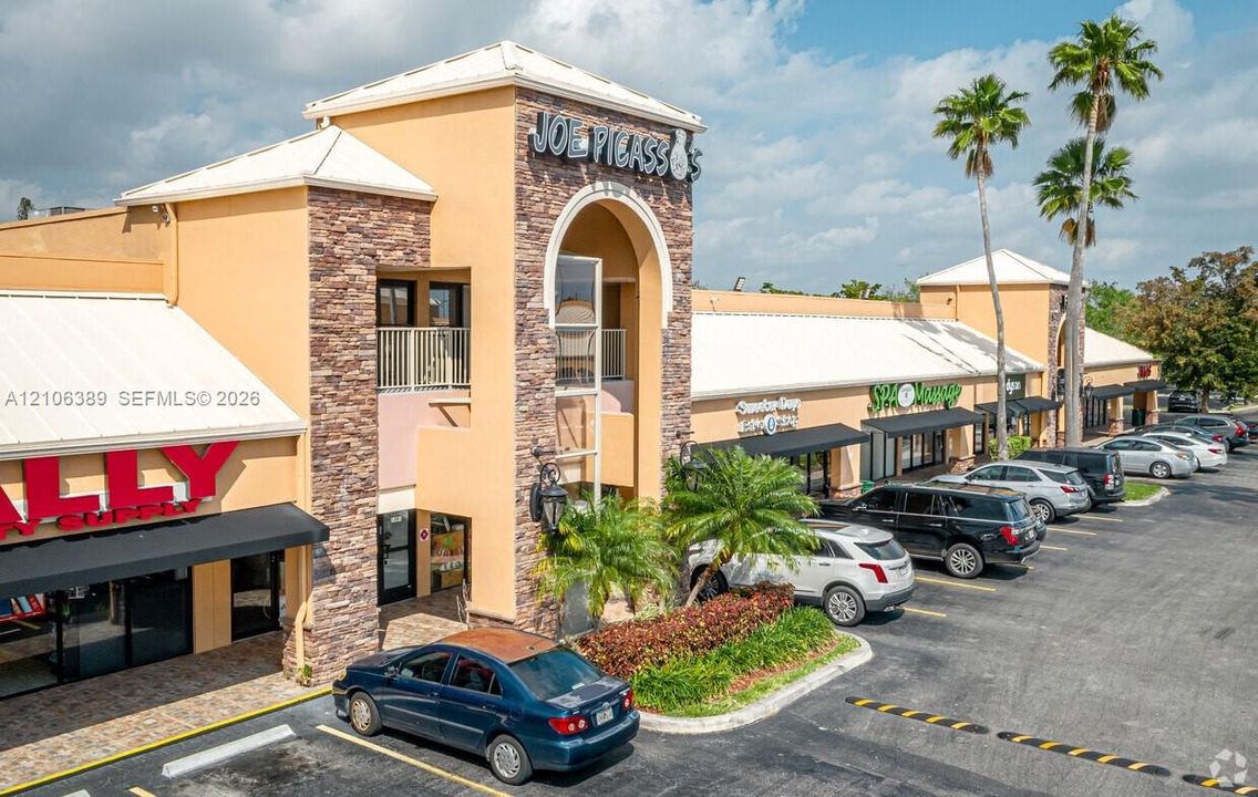 Commercial retail center featuring a stucco and stone veneer exterior, arched entryway, metal awnings, and a dedicated asphalt parking lot with established landscaping