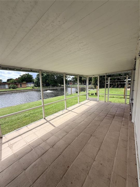 Screened-in patio featuring tile flooring, a painted beadboard ceiling, and direct water frontage
