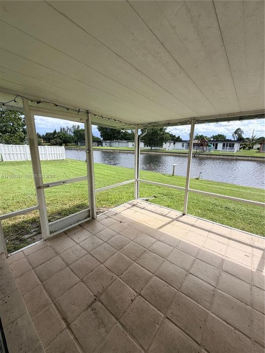 Screened-in porch with tile flooring, elevated ceiling, and direct water frontage