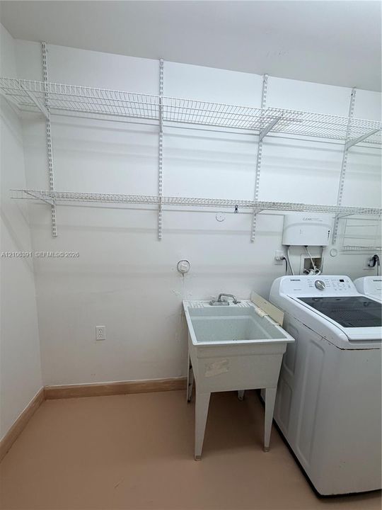Utility space featuring white wire wall-mounted shelving and a basin sink with a dual-handle faucet