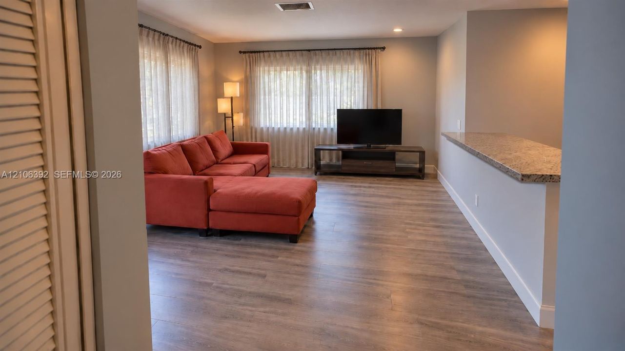 Living area featuring wood-finish flooring, recessed lighting, and a stone-surface breakfast bar