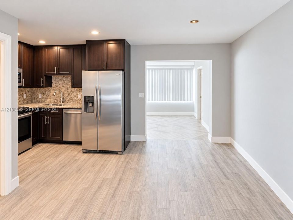 Kitchen featuring dark cabinetry, stone-finish countertops, stainless steel appliances, and wood-finish flooring