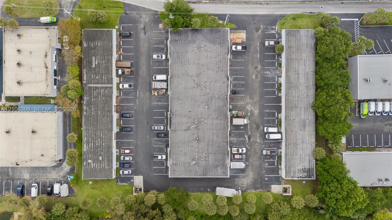 Aerial view of industrial site featuring three structures with flat roofing, dedicated asphalt parking lots, and perimeter landscaping