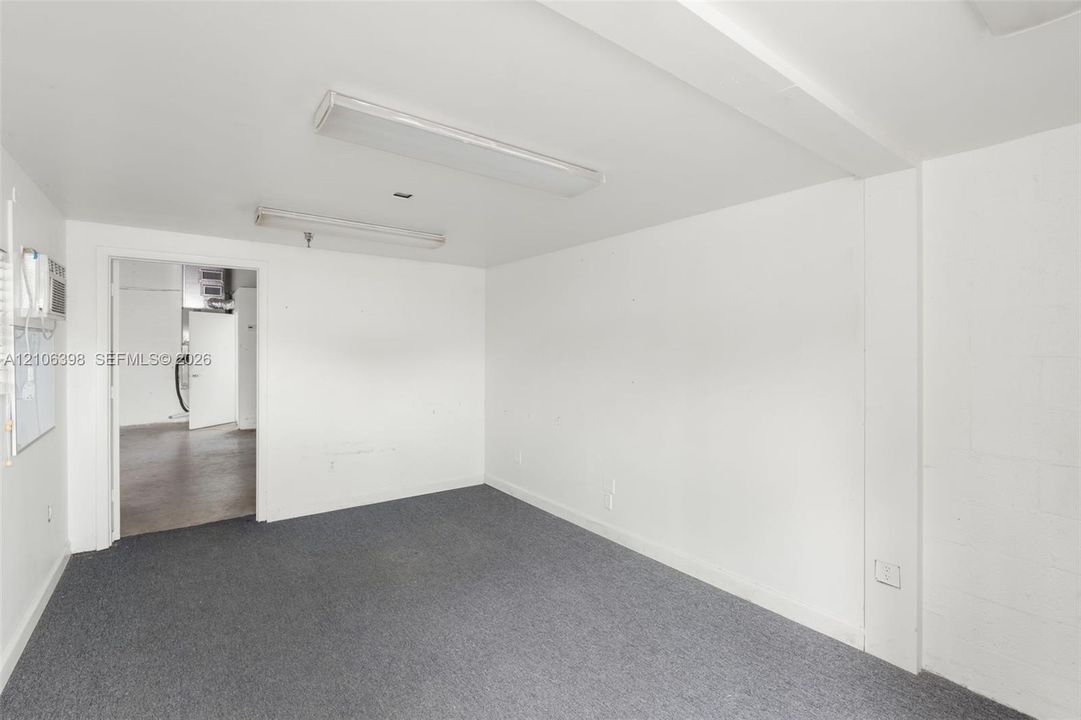 Interior space featuring neutral wall-to-wall carpeting, painted masonry walls, and dual ceiling-mounted fluorescent lighting fixtures