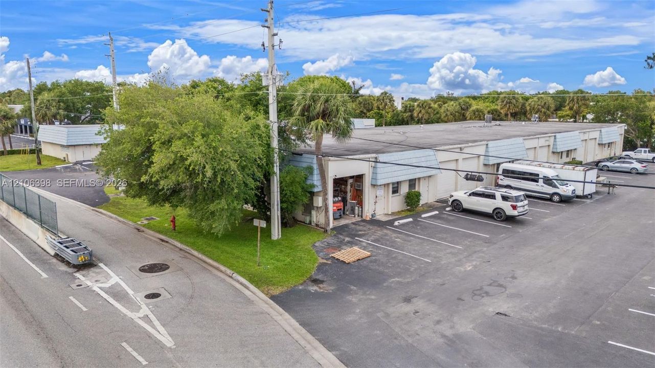 Commercial building featuring a flat roofline, asphalt-paved surface lot, and multiple bay-door entrances