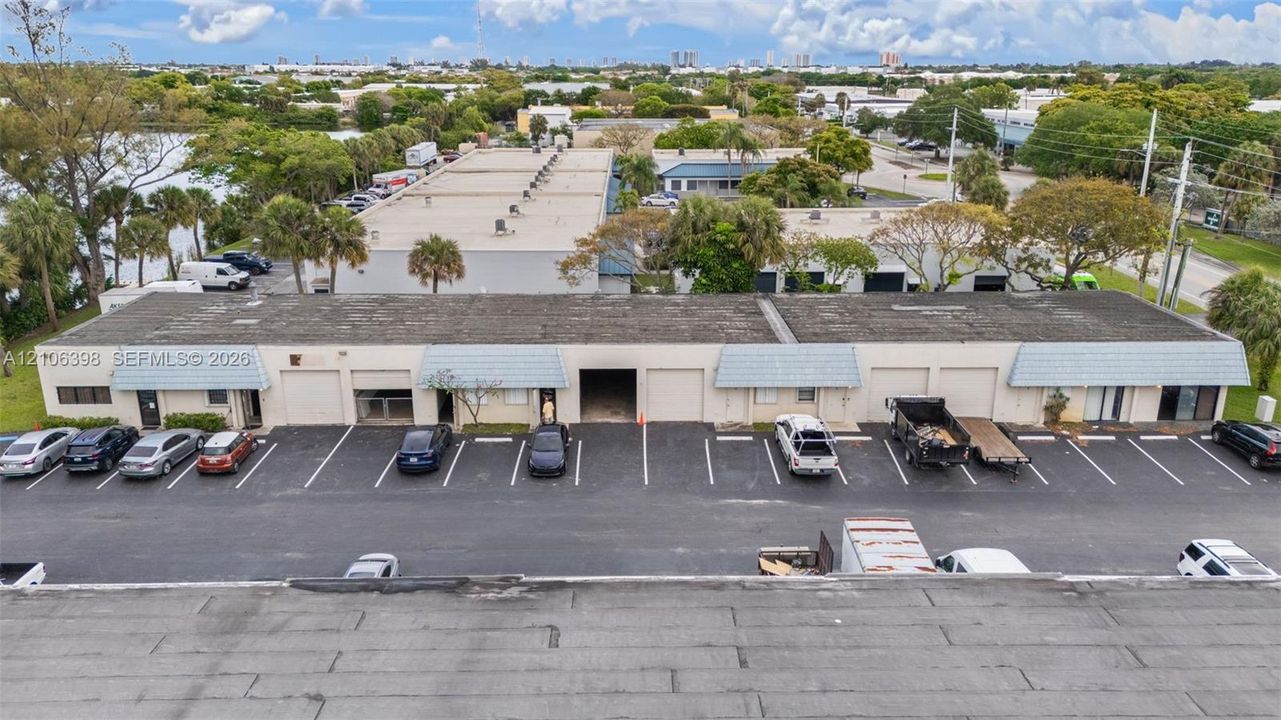 Single-story commercial building featuring multiple overhead roll-up doors, metal-finished entrance awnings, and an expansive asphalt-paved parking lot