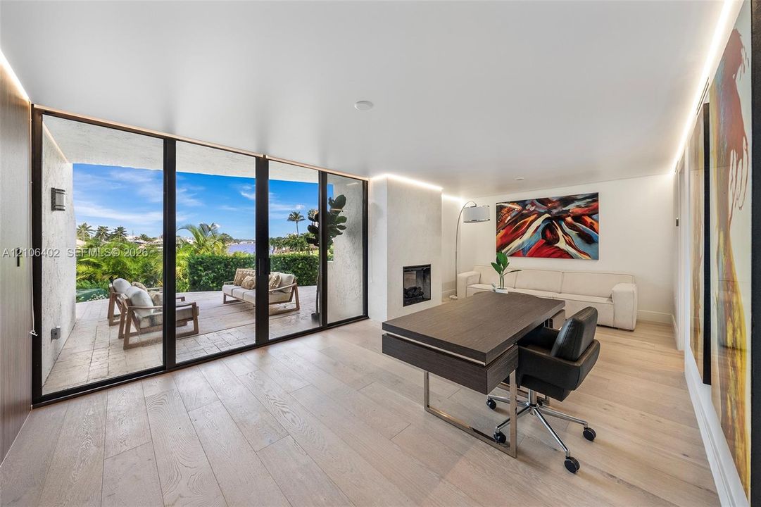 Floor-to-ceiling glass sliding doors, wood-finish flooring, recessed cove lighting, and a modern built-in fireplace