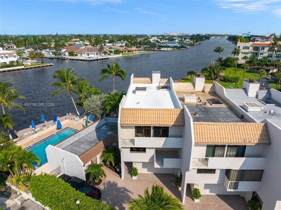 Waterfront property featuring a private swimming pool, multi-level terraces, tile roof, and paved driveway
