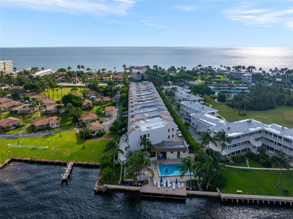 Waterfront multi-story residential complex featuring a swimming pool, private wooden dock, and extensive landscaped grounds