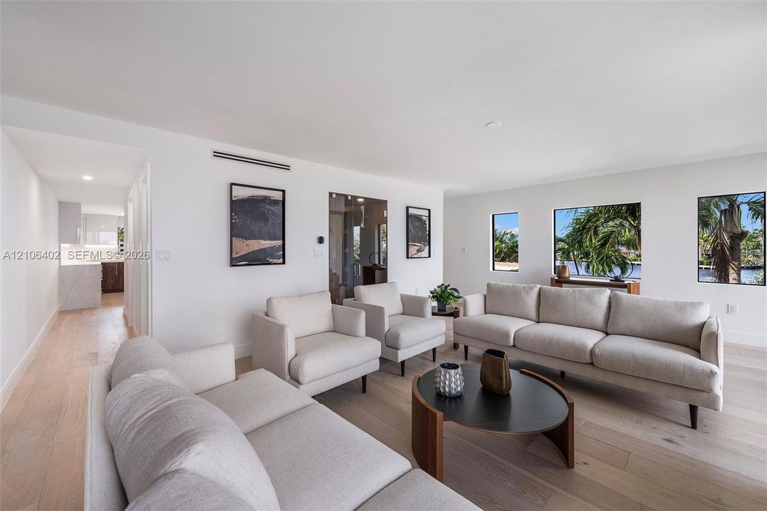 Living area featuring light wood-finish flooring, recessed ceiling lighting, and large windows with outdoor scenery