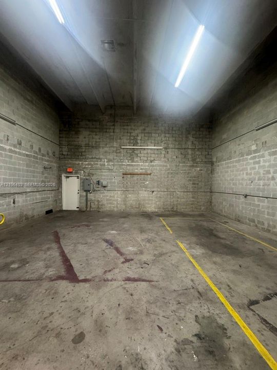 Industrial interior featuring high ceilings, concrete masonry unit walls, a concrete floor, and linear LED lighting