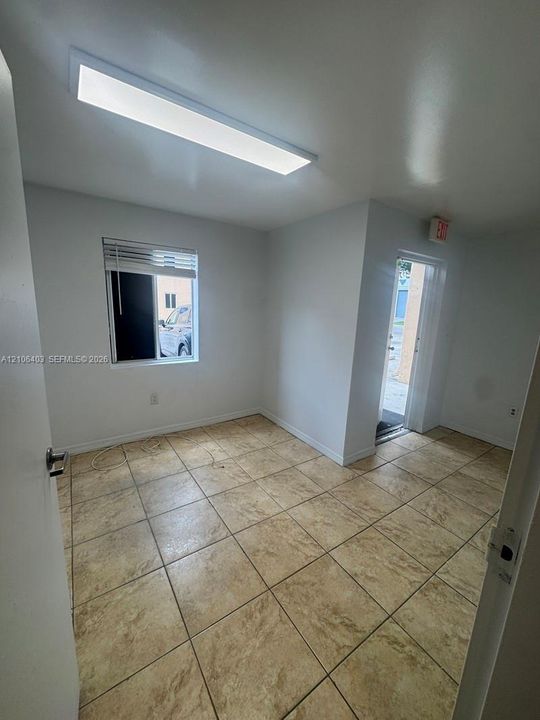 Neutral-toned tile flooring, recessed rectangular ceiling lighting, and a single-pane window with integrated blinds