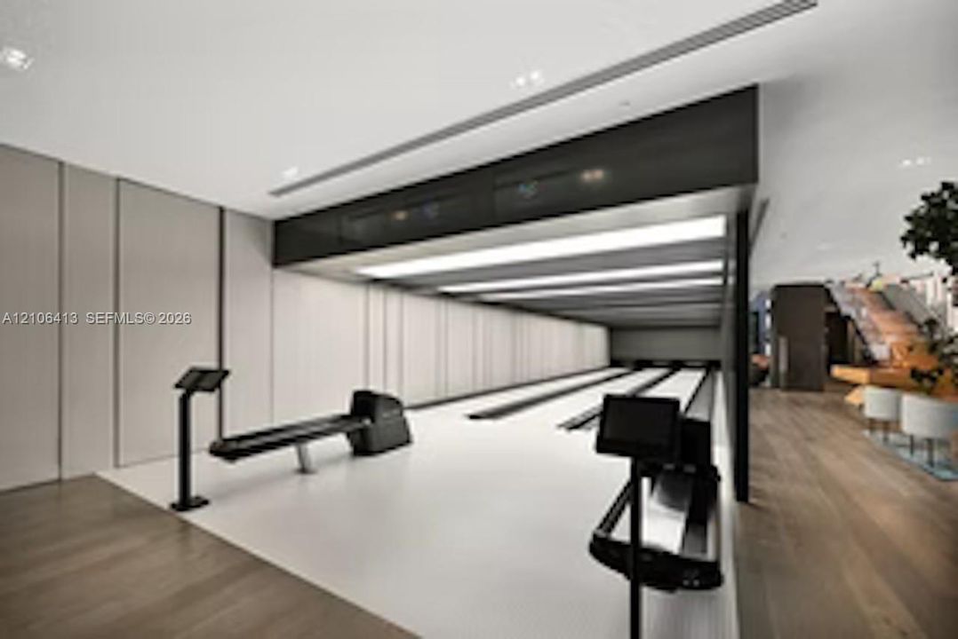 Multi-lane bowling alley featuring recessed ceiling lighting, wood-finish flooring, paneled wall detailing, and integrated console displays