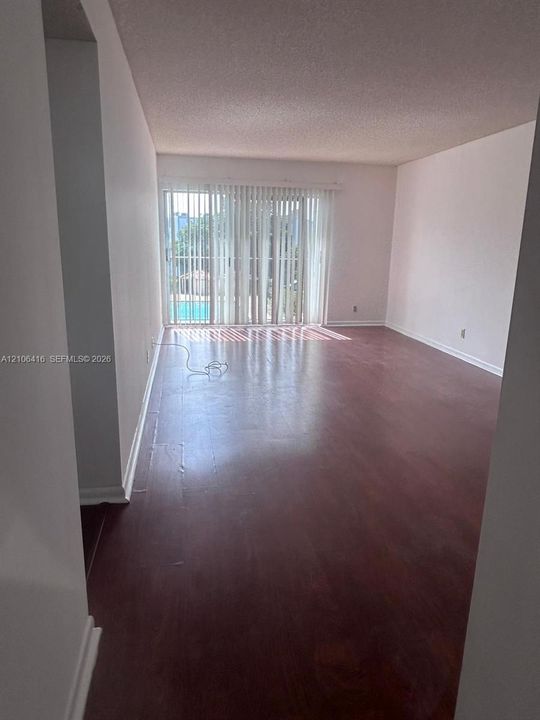 Interior room featuring wood-finish flooring, smooth ceilings, and sliding glass doors with vertical blinds