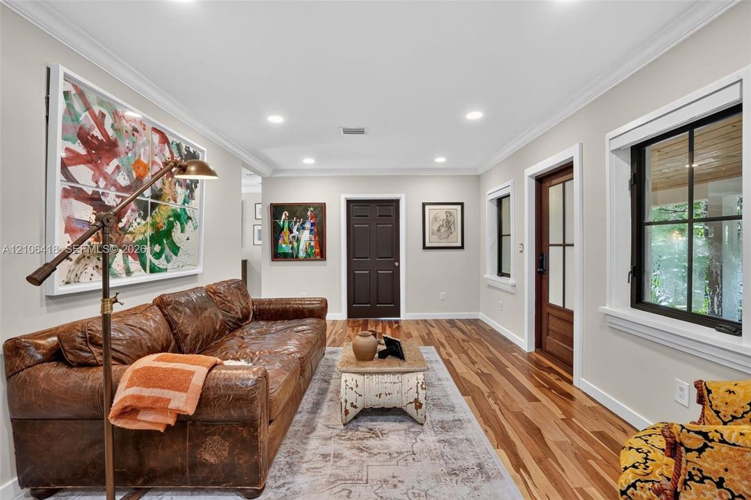 Interior space featuring wood-finish flooring, recessed lighting, crown molding, multi-pane windows with black frames, and a multi-panel door with glass inserts