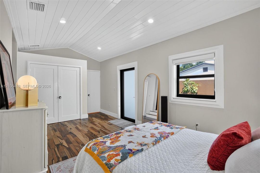 Vaulted ceiling with tongue-and-groove planking, recessed lighting, wood-finish flooring, and a glass-paneled exterior door