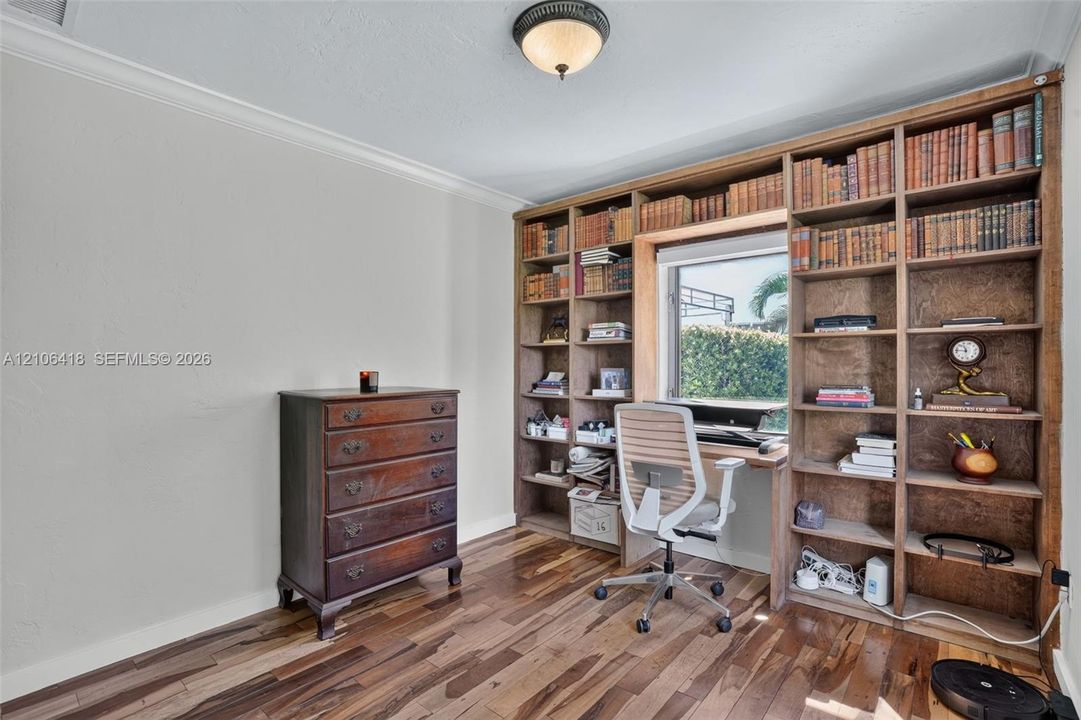 Floor-to-ceiling built-in wood shelving with integrated desk workspace, wood-finish flooring, and semi-flush mount ceiling lighting