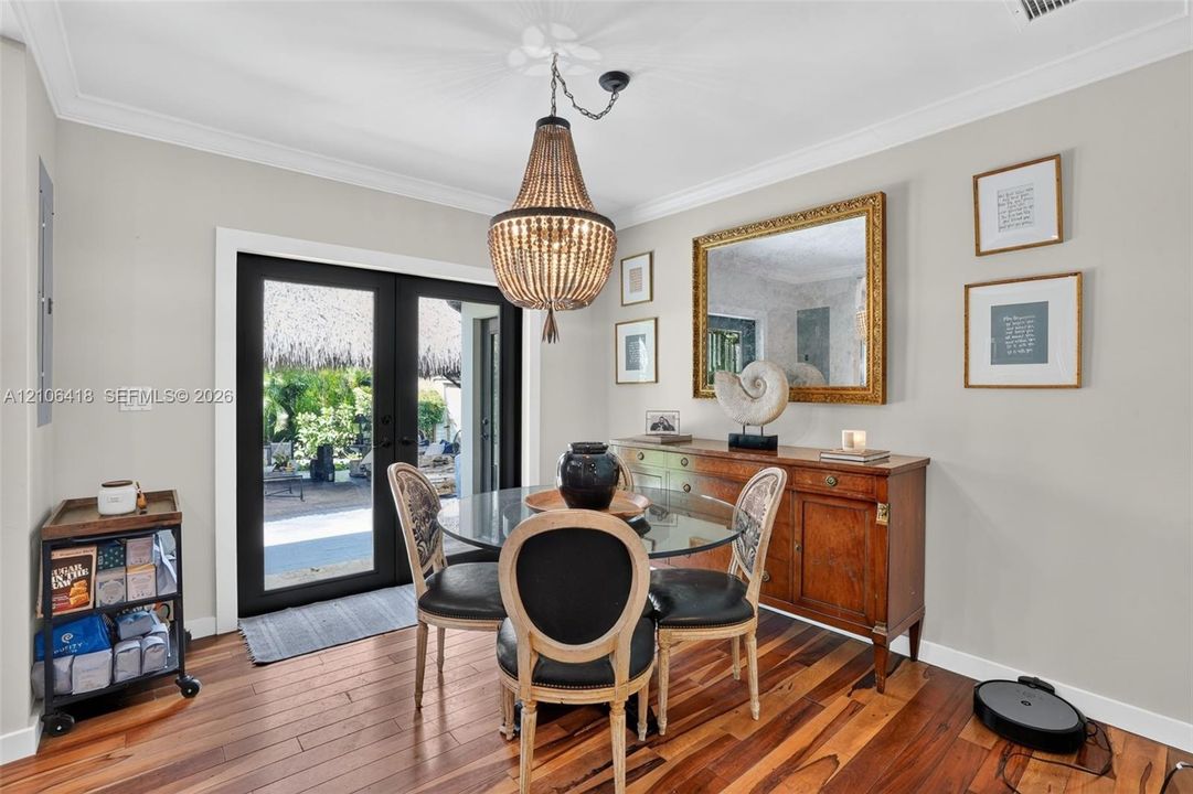Dining area featuring wood-finish flooring, crown molding, and a tiered beaded chandelier
