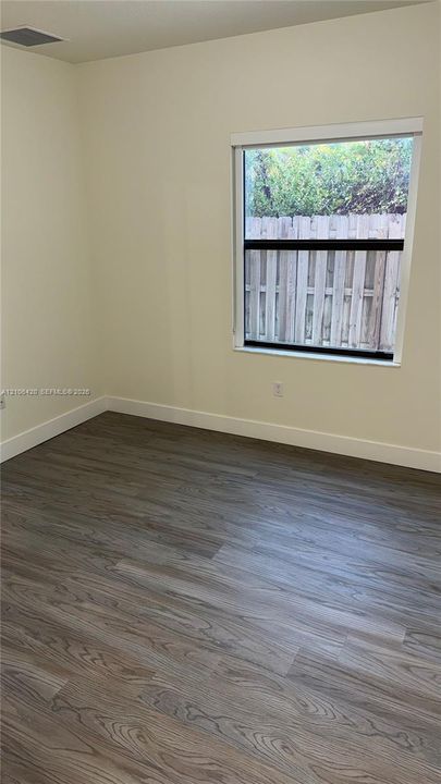 Room featuring wood-finish flooring, neutral wall paint, and a single-pane window with a white frame
