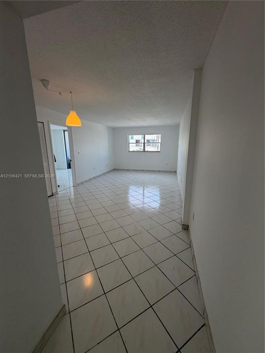 Interior space featuring white diagonal tile flooring, smooth ceilings, a dual-pane window, and a pendant light fixture