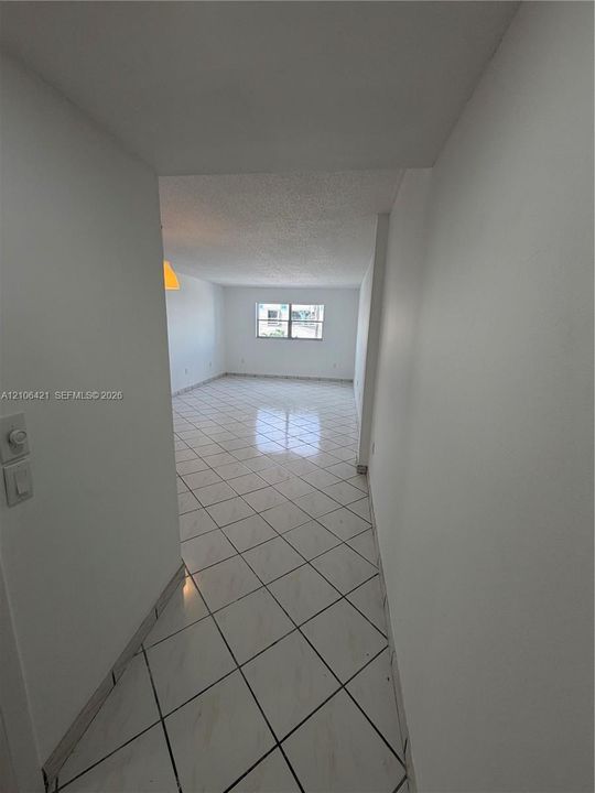 Open-concept area featuring light-toned, diagonal-set tile flooring, smooth ceilings, and white wall finishes