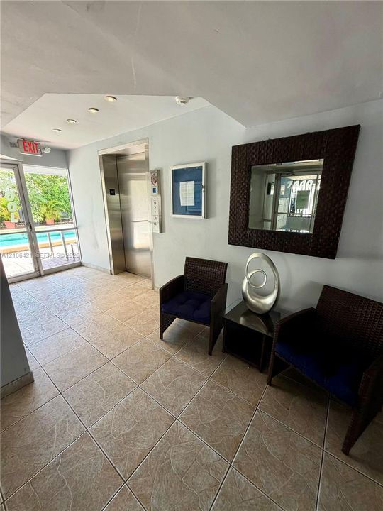 Common area lobby featuring large-format tile flooring, a brushed metal elevator, and recessed ceiling lighting