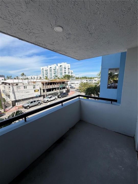 Private balcony featuring a concrete floor, stucco ceiling with recessed lighting, and a black metal railing