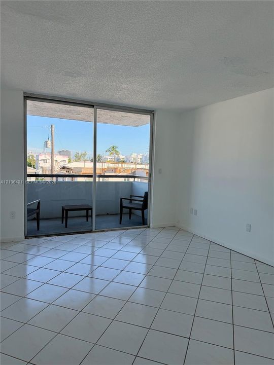 Interior space featuring large-format ceramic tile flooring, sliding glass door, and a private balcony with metal railing