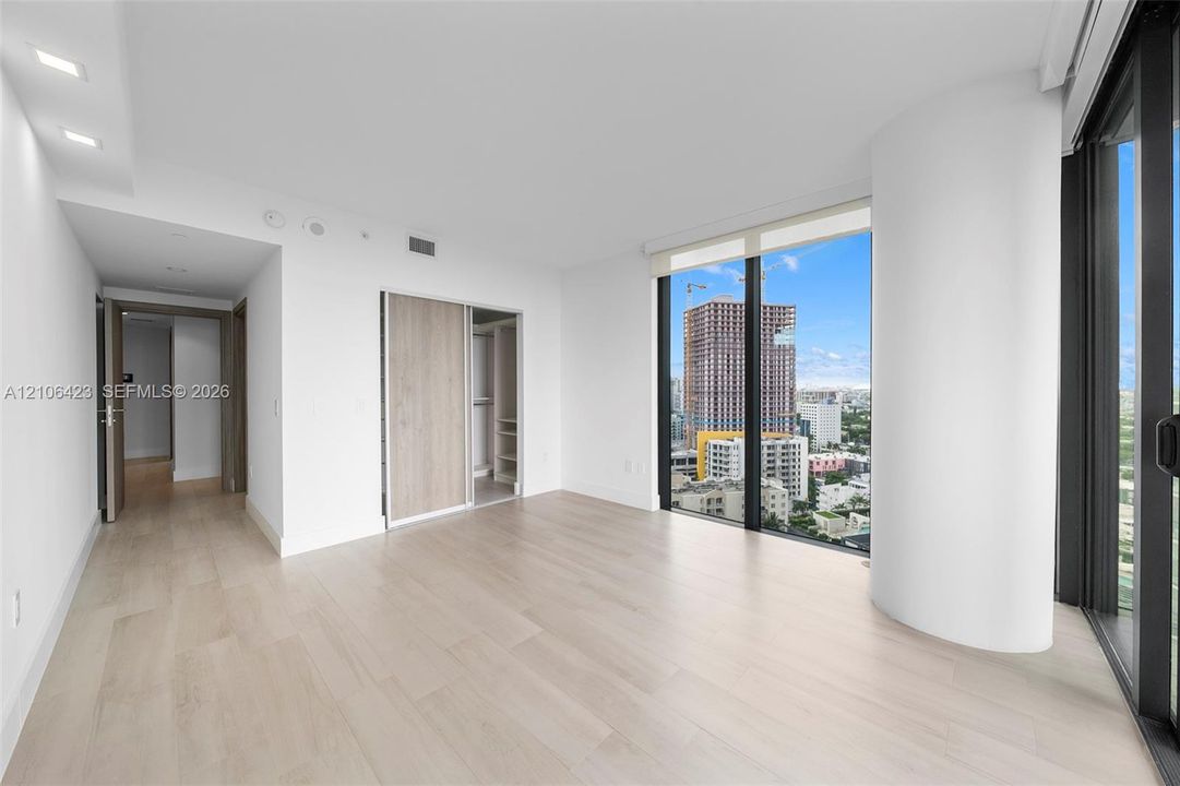 Floor-to-ceiling windows, wood-finish flooring, recessed lighting, and built-in closet with sliding doors
