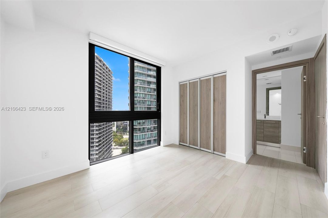 Floor-to-ceiling windows, wood-finish flooring, built-in closet with wood-finish paneling, and interior wood-finish doors