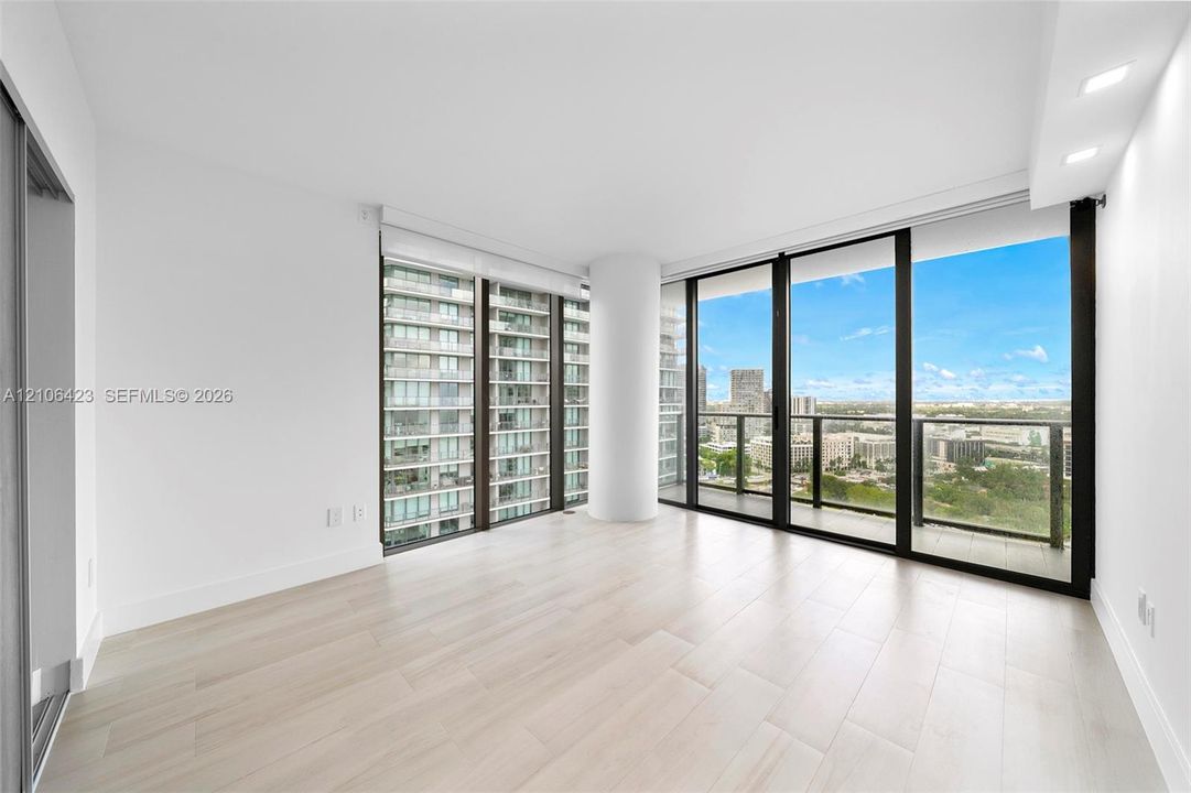 Floor-to-ceiling windows, wood-finish flooring, recessed lighting, and a private balcony with metal railings