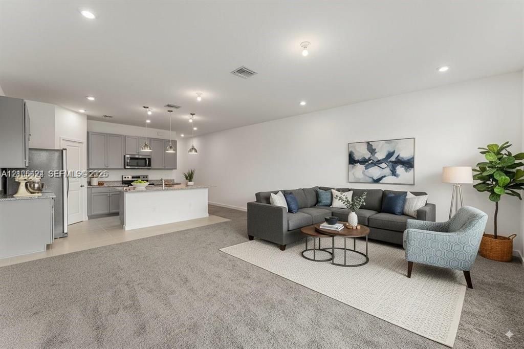 Kitchen featuring grey cabinetry, stone countertops, a center island, and recessed lighting throughout the area